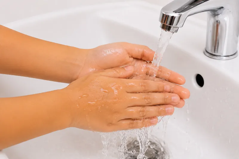Rinsing hands with clean running water.